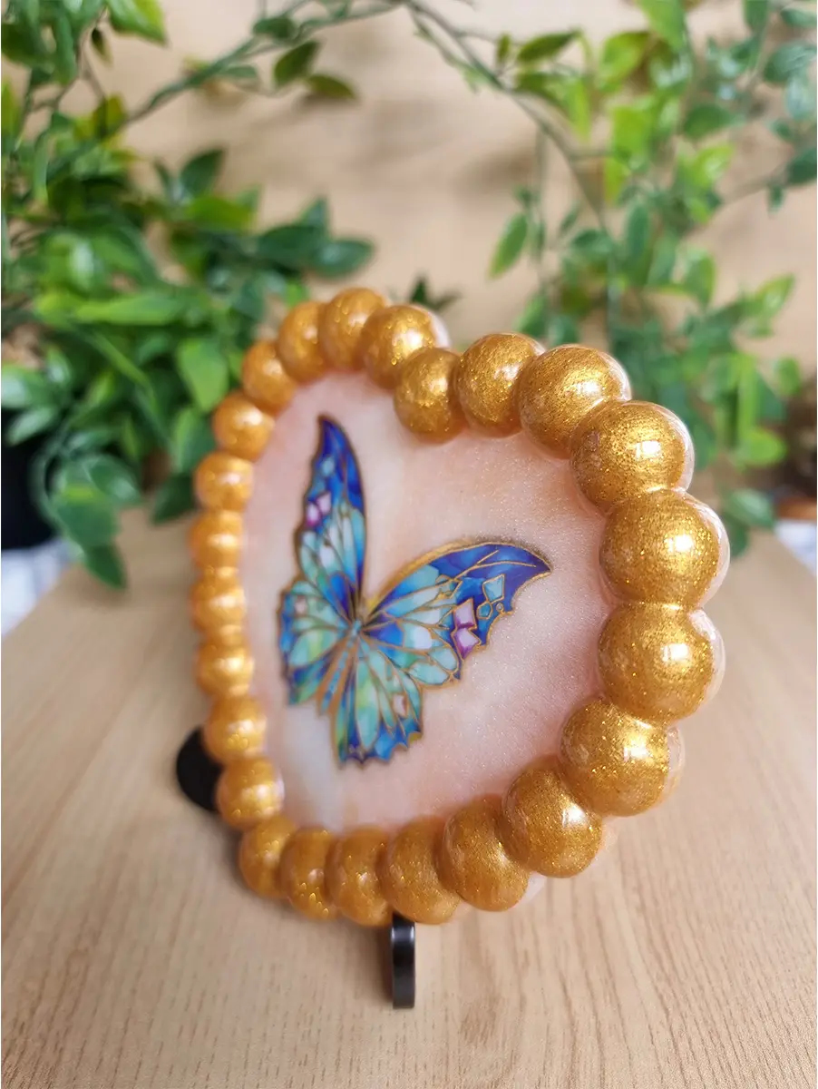 Heart-shaped craft with iridescent blue butterfly and gold beaded border.