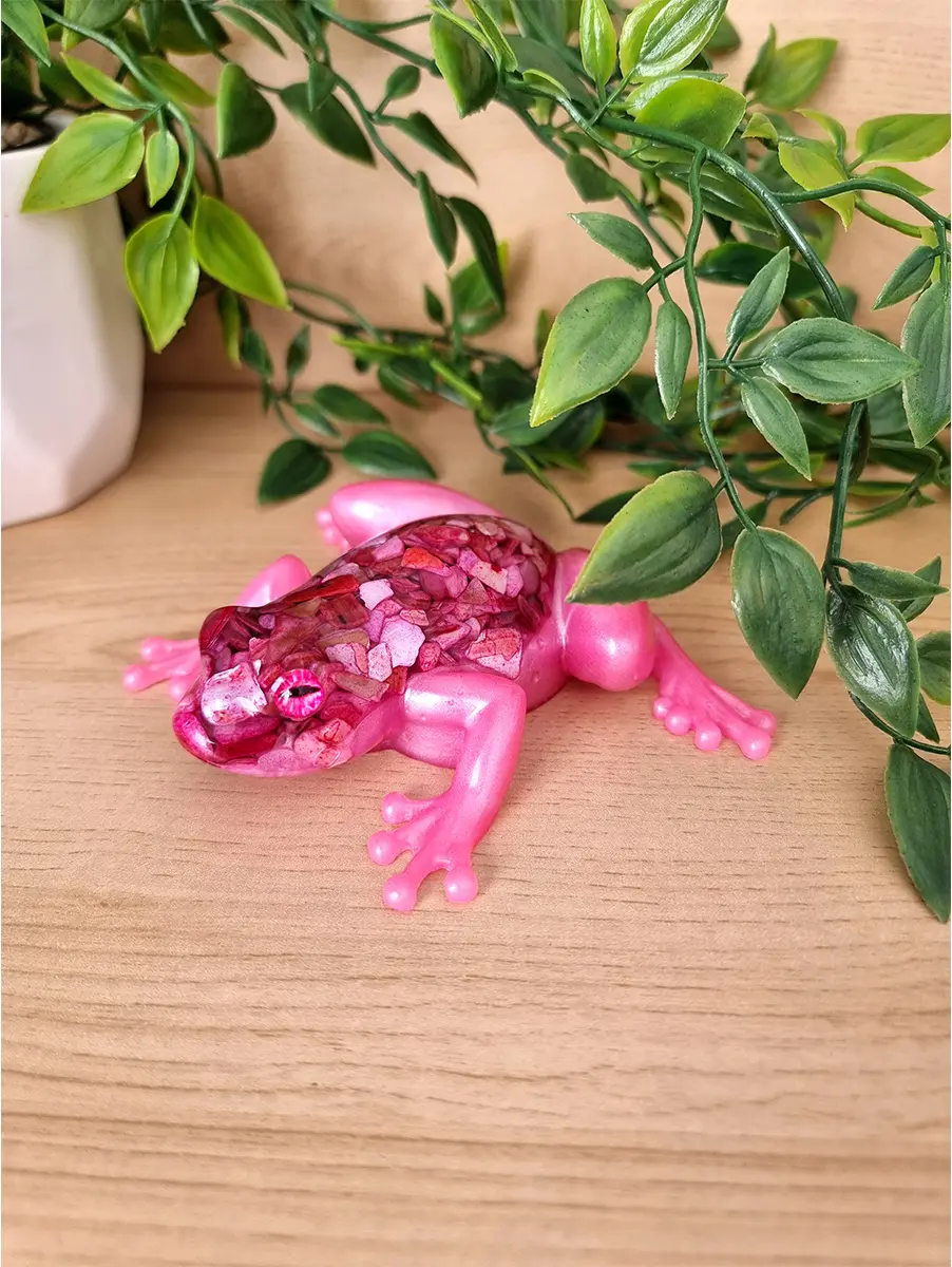 A unique pink resin frog sculpture with a mosaic-like textured back, featuring shimmering pink and red fragments and eye details.