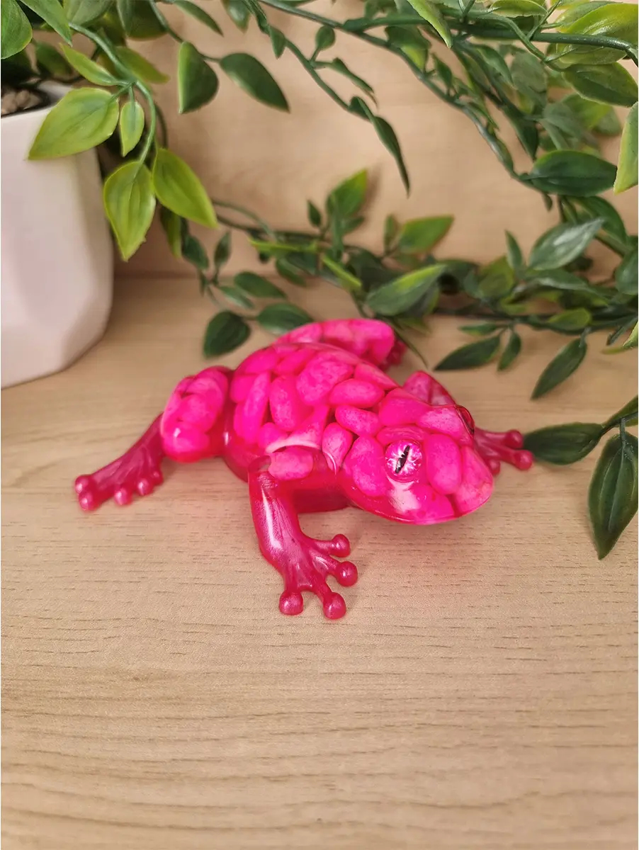 Vibrant fuchsia textured resin gecko art piece with glossy finish and intricate eyes, resting on a wooden surface.