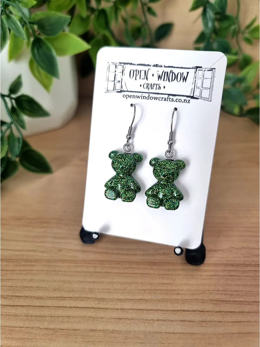 Sparkling emerald green gummy teddy bear resin dangle earrings shimmer with metallic flecks, showcasing artisanal craftsmanship.