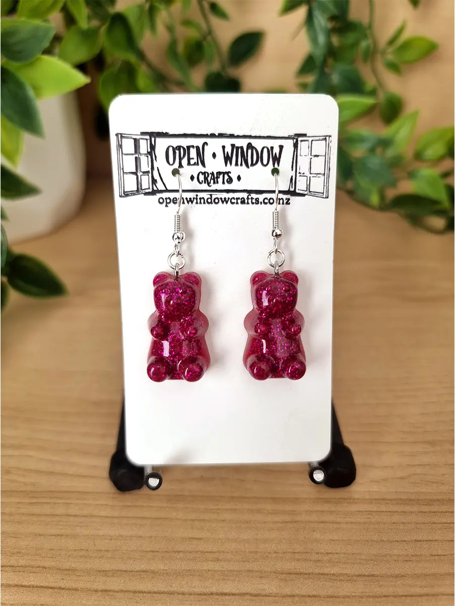 Sparkling fuchsia gummy bear earrings dangle from silver hooks.