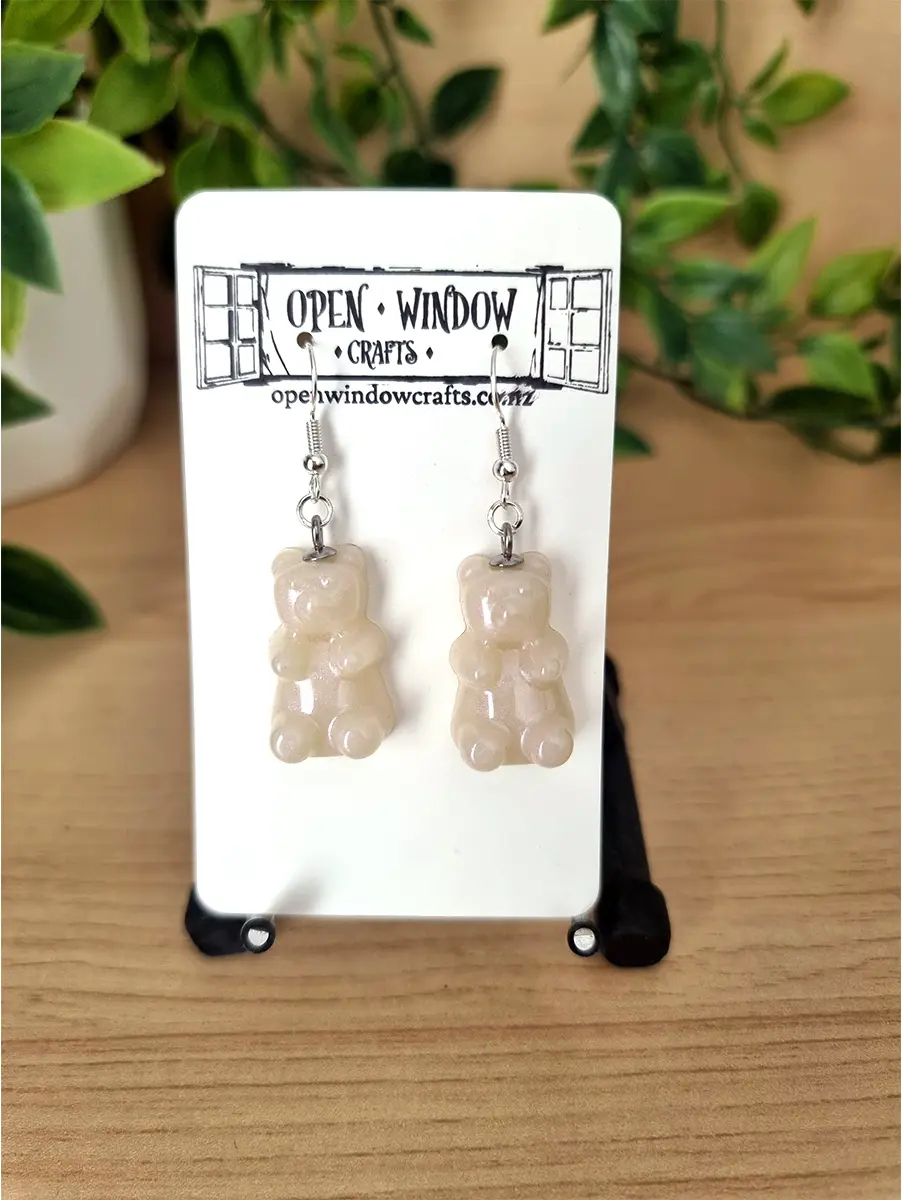 Creamy white gummy bear resin drop earrings shimmer under light.