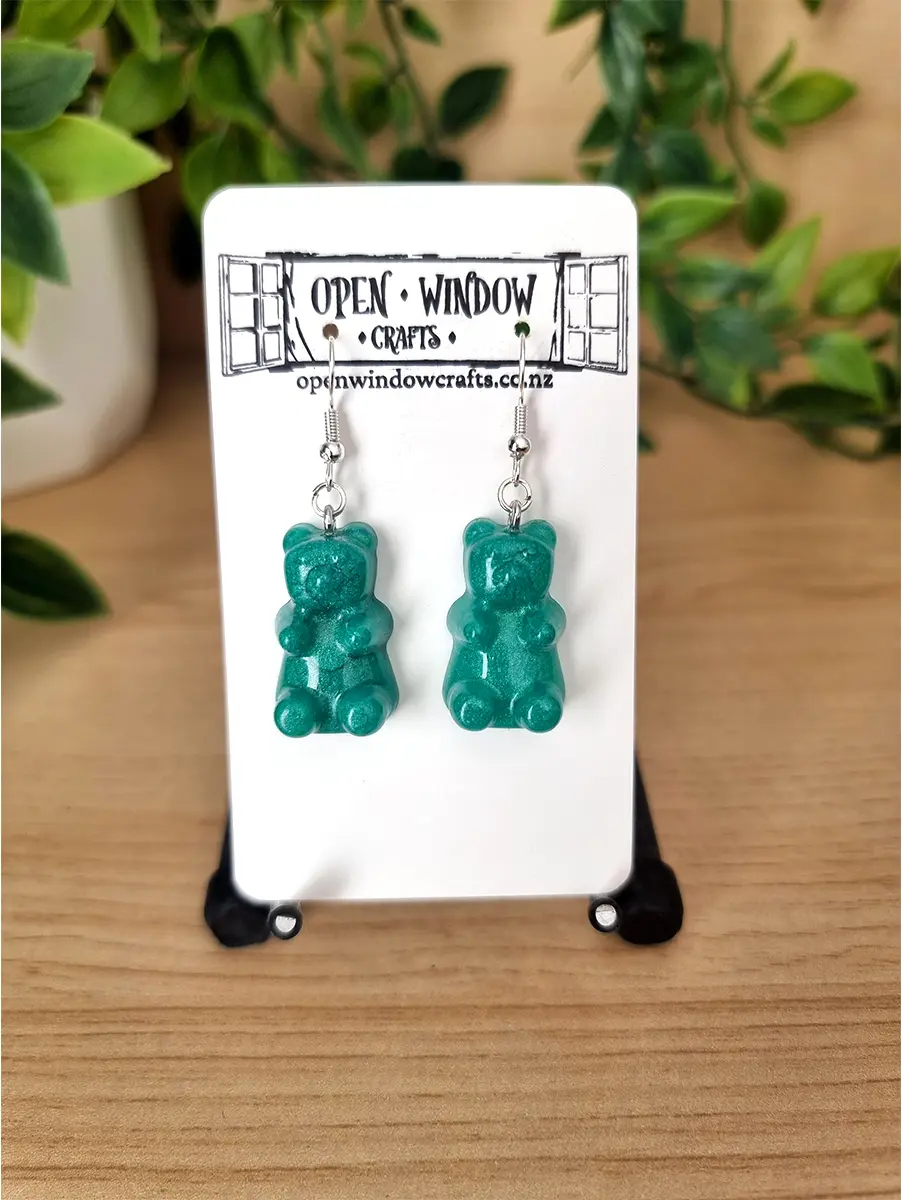 Teal gummy bear resin earrings dangle from silver hooks.