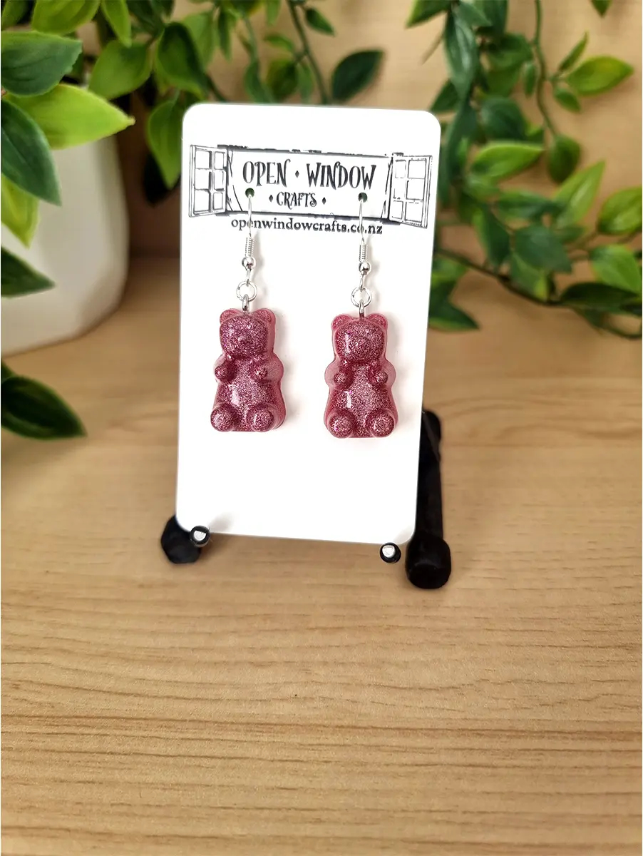 Raspberry gummy bear resin earrings shimmer with glitter and hang from silver hooks.