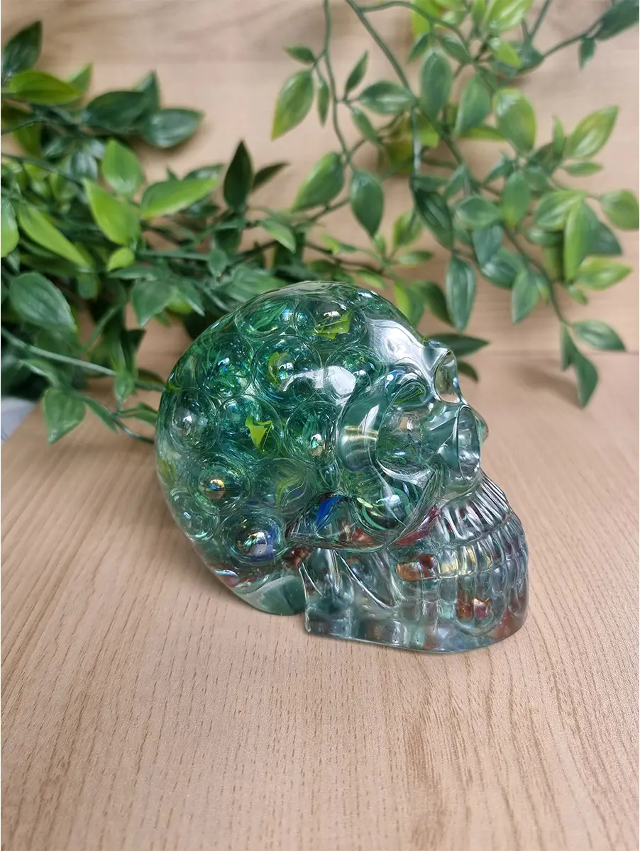 Resin skull sculpture embedded with colourful marbles and glass accents sits on a wooden surface.