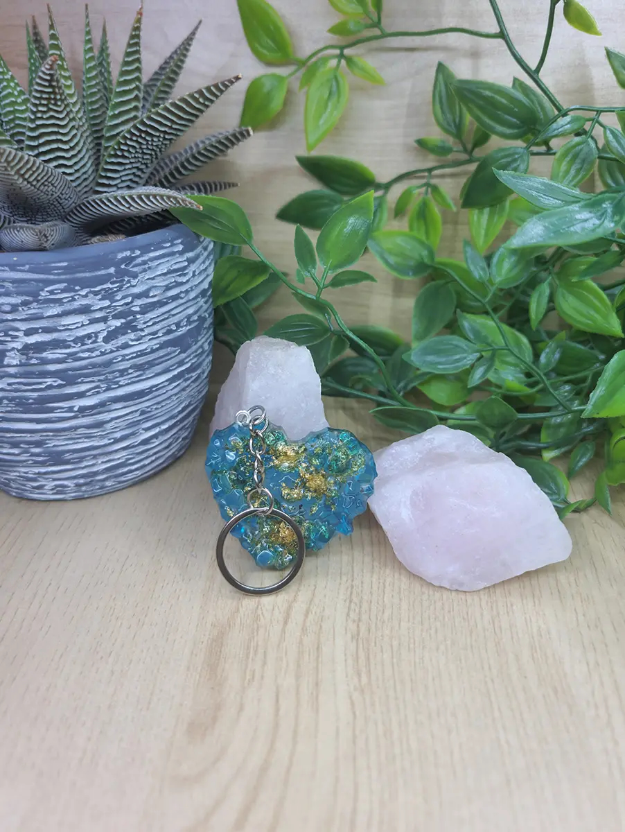 Aqua blue heart-shaped resin keychain with embedded gold leaf, affixed to a silver keyring.