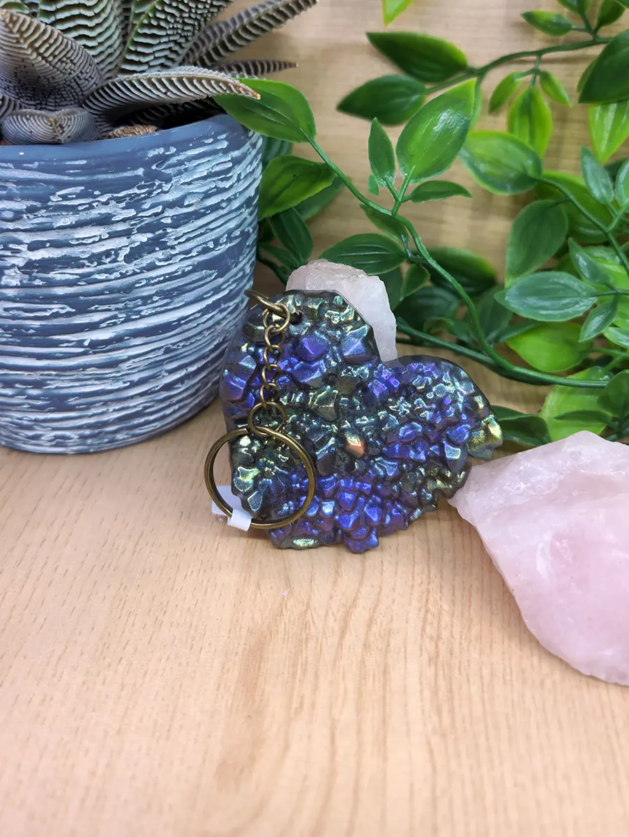 Iridescent heart-shaped keychain features shimmering blues and purples with a textured, geode-like surface.