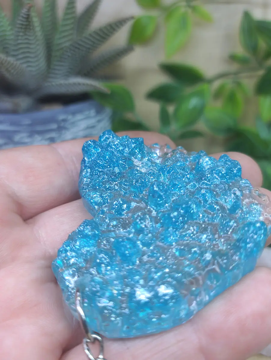 Teal crystal geode resin keychain sparkling with vibrant blue hues and crystalline texture.