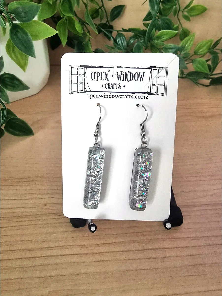Silver glitter resin bar earrings dangle from fish hook clasps on a white display card.