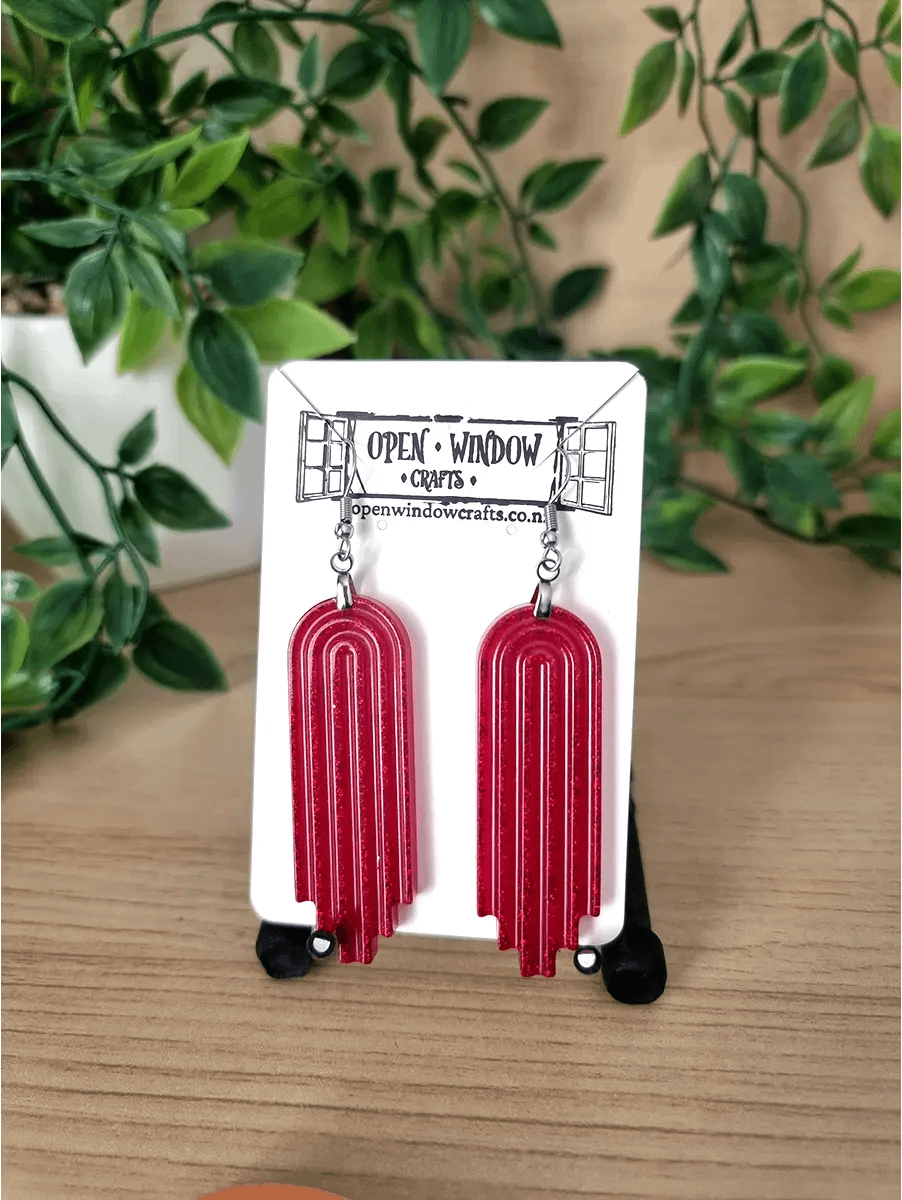 Shiny red resin earrings feature a tiered arch geometric design hanging from silver hooks.